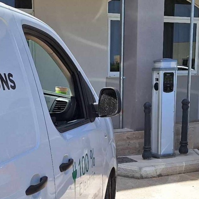 White Quantum charger installed outdoors next to a Solar Solutions van