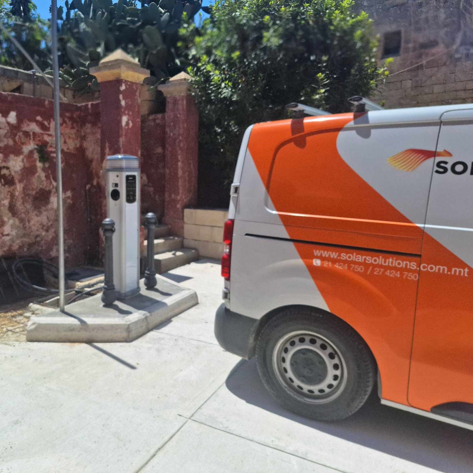 White Quantum charger installed outdoors next to a Solar Solutions van